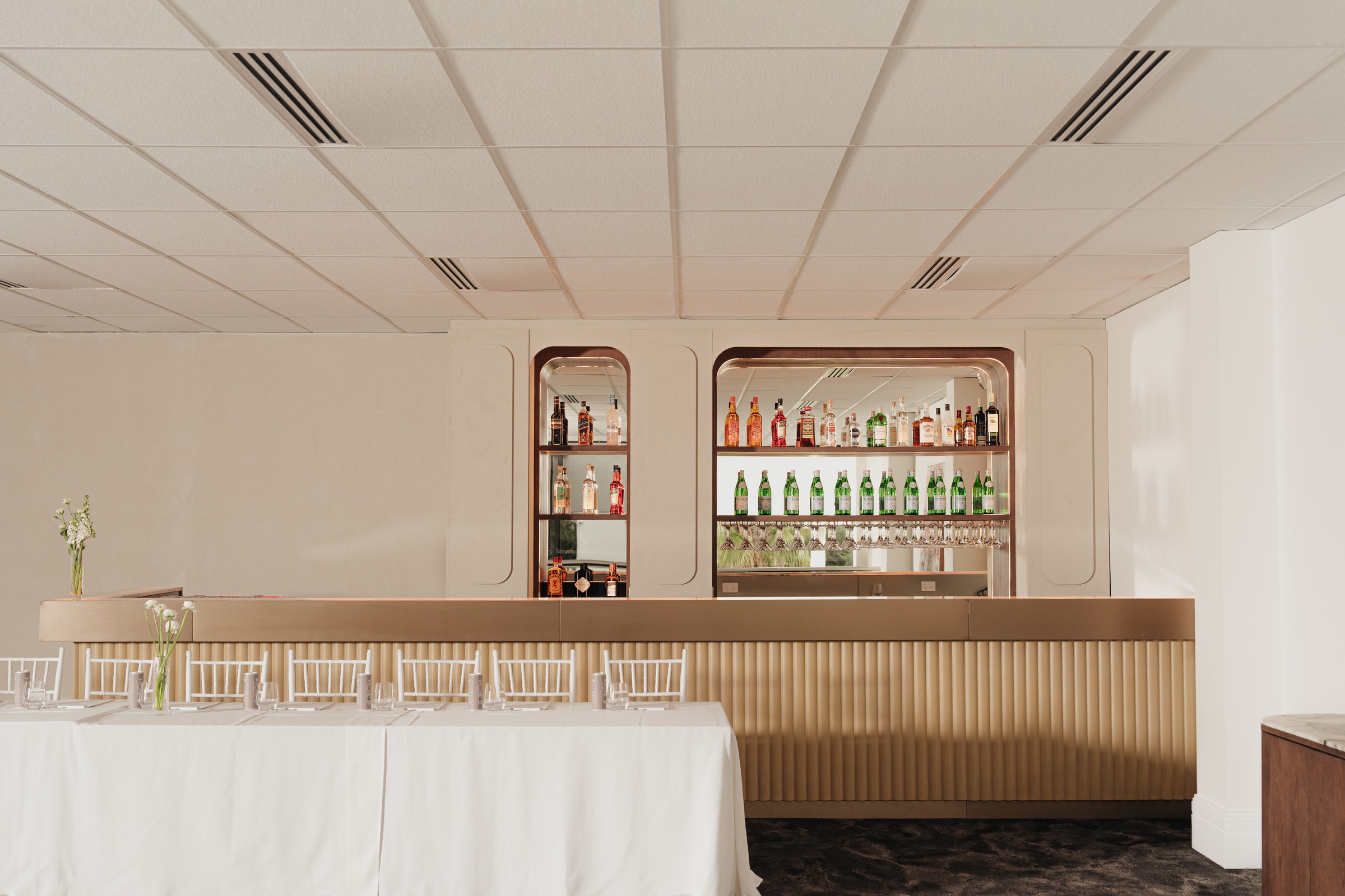 Arched bar with Aperol and spirits behind a long white table at Melrose Events