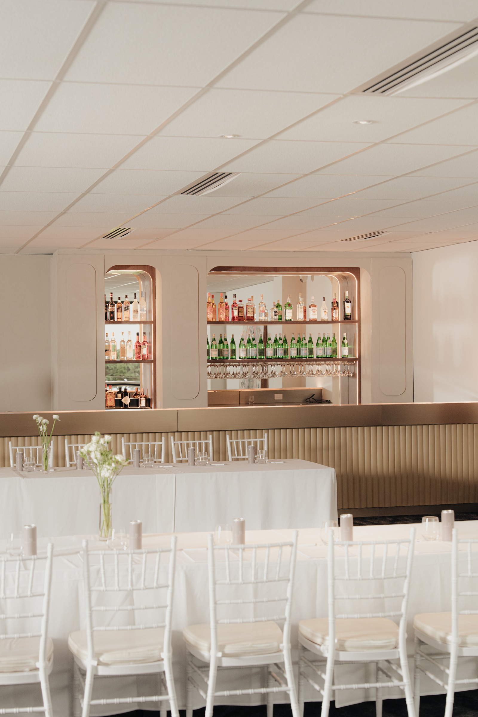 Backlit arched bar niches stocked with Aperol, spirits and glassware at Melrose Events