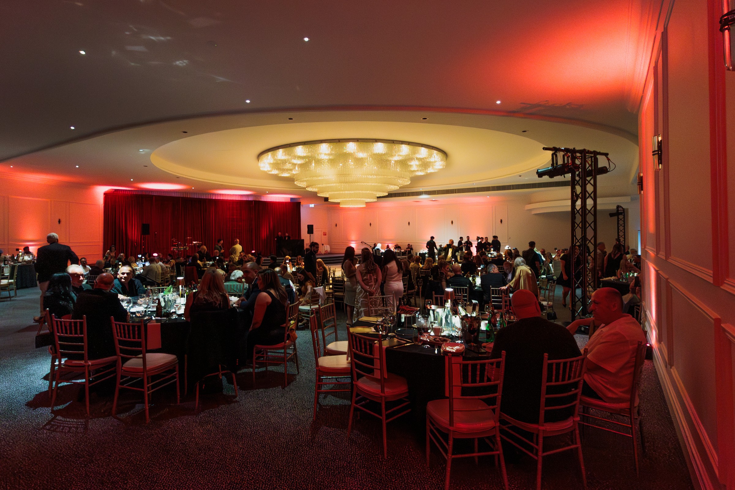 Corporate dinner in the Melrose ballroom with red-lit walls and gold chairs