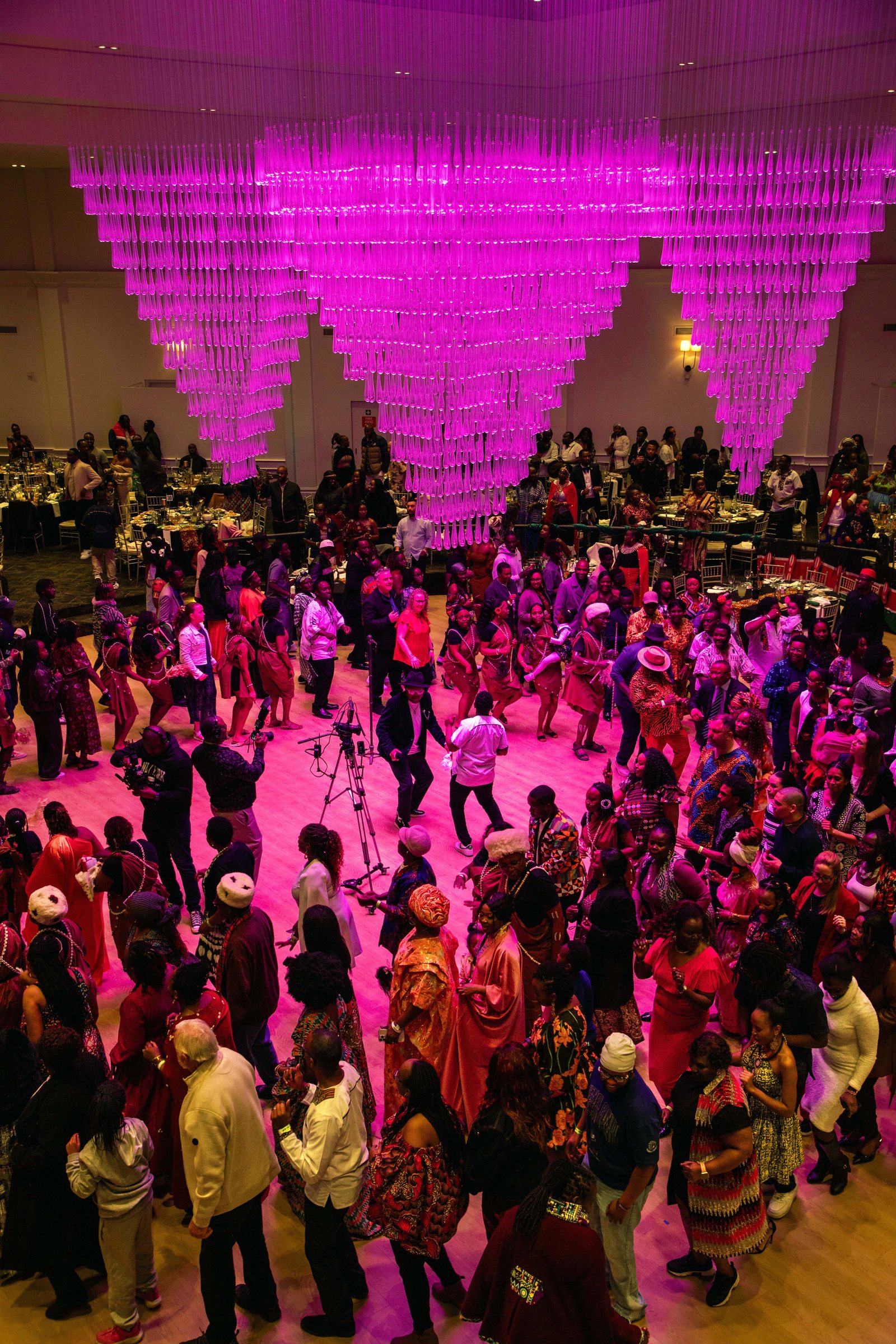 Crowded dance floor beneath pink chandeliers at a cultural celebration at Melrose