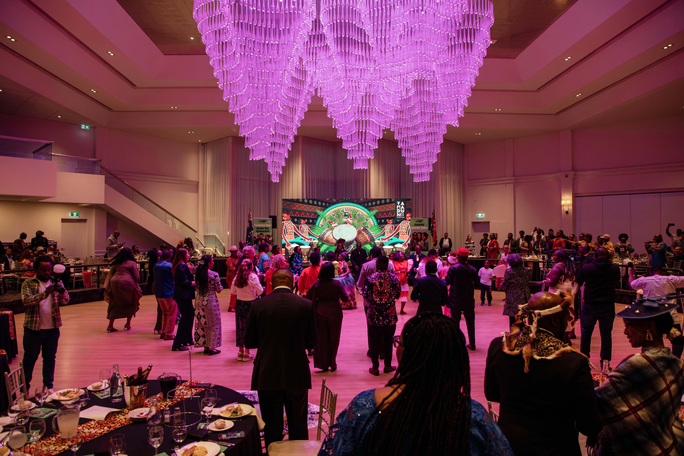 Wide view of the Melrose ballroom in pink lighting during a cultural community event