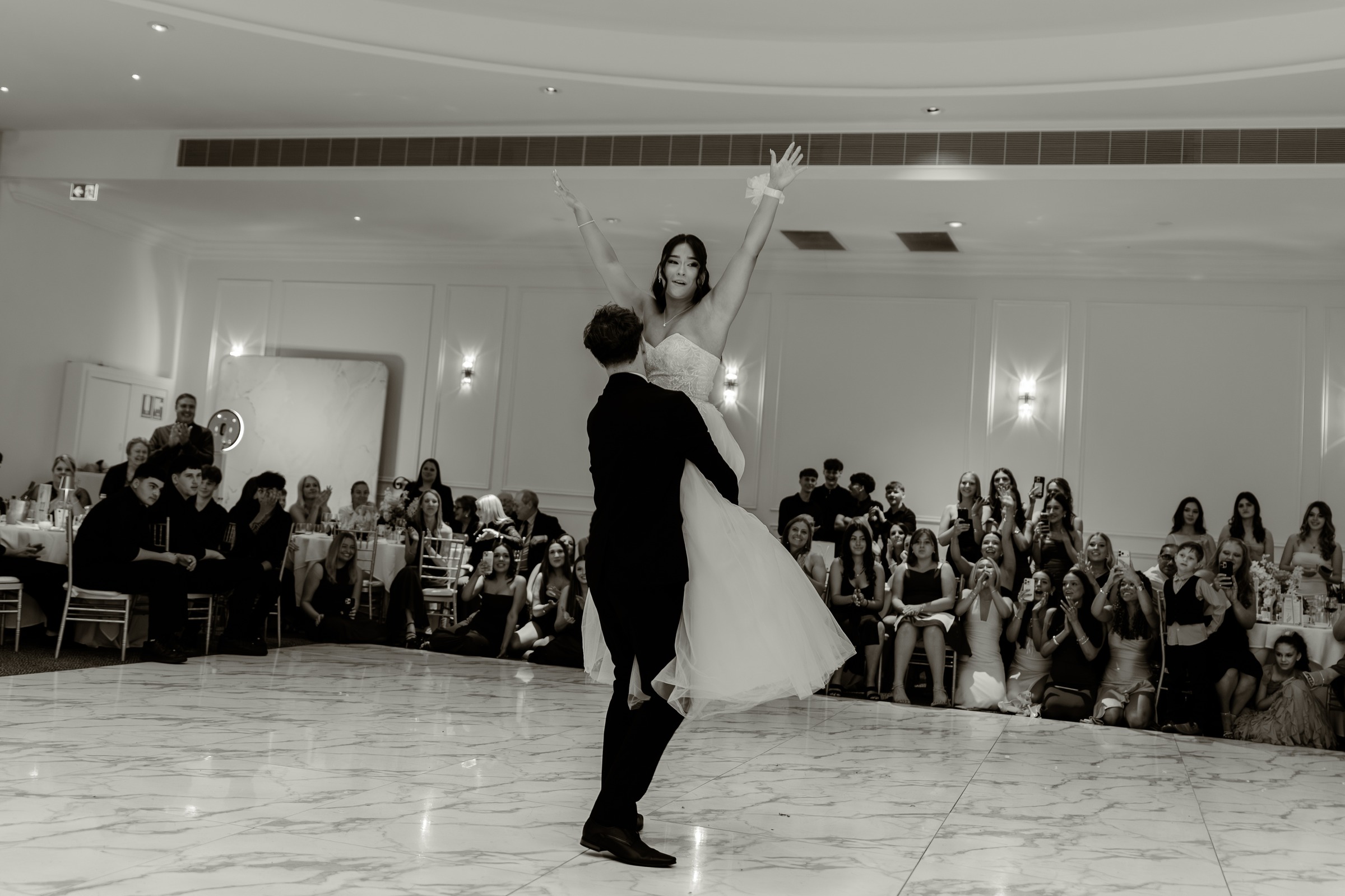 Debutante dipped by her partner in front of seated guests at a debutante ball