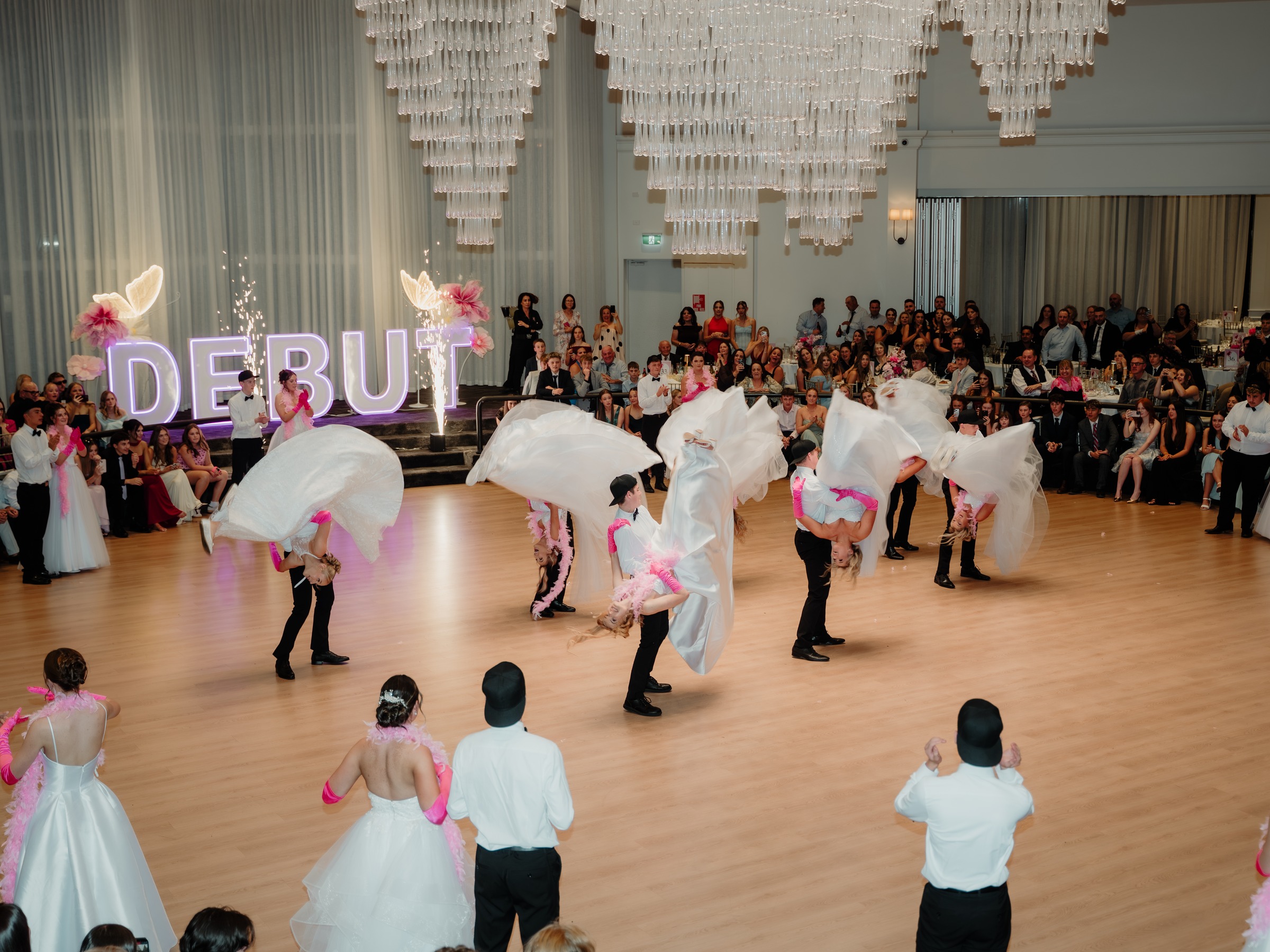 Debutante gowns fanned out across the dance floor in front of the Debut sign