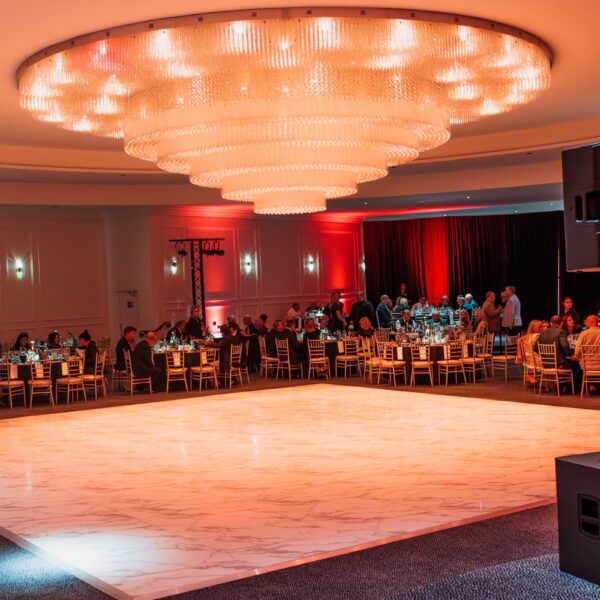 Ballroom dance floor under the tiered chandelier with guests seated around it