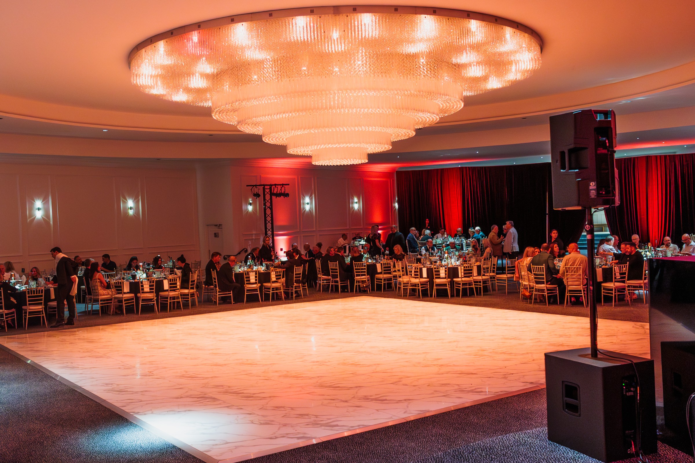 Ballroom dance floor under the tiered chandelier with guests seated around it