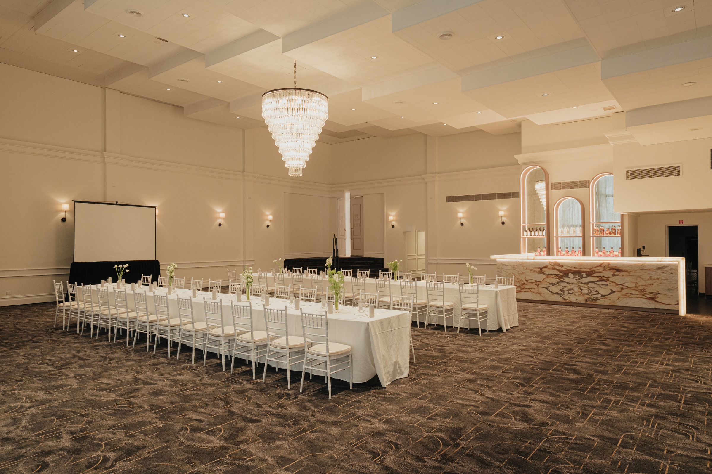 Magnolia Room set with two long white tables beneath the chandelier