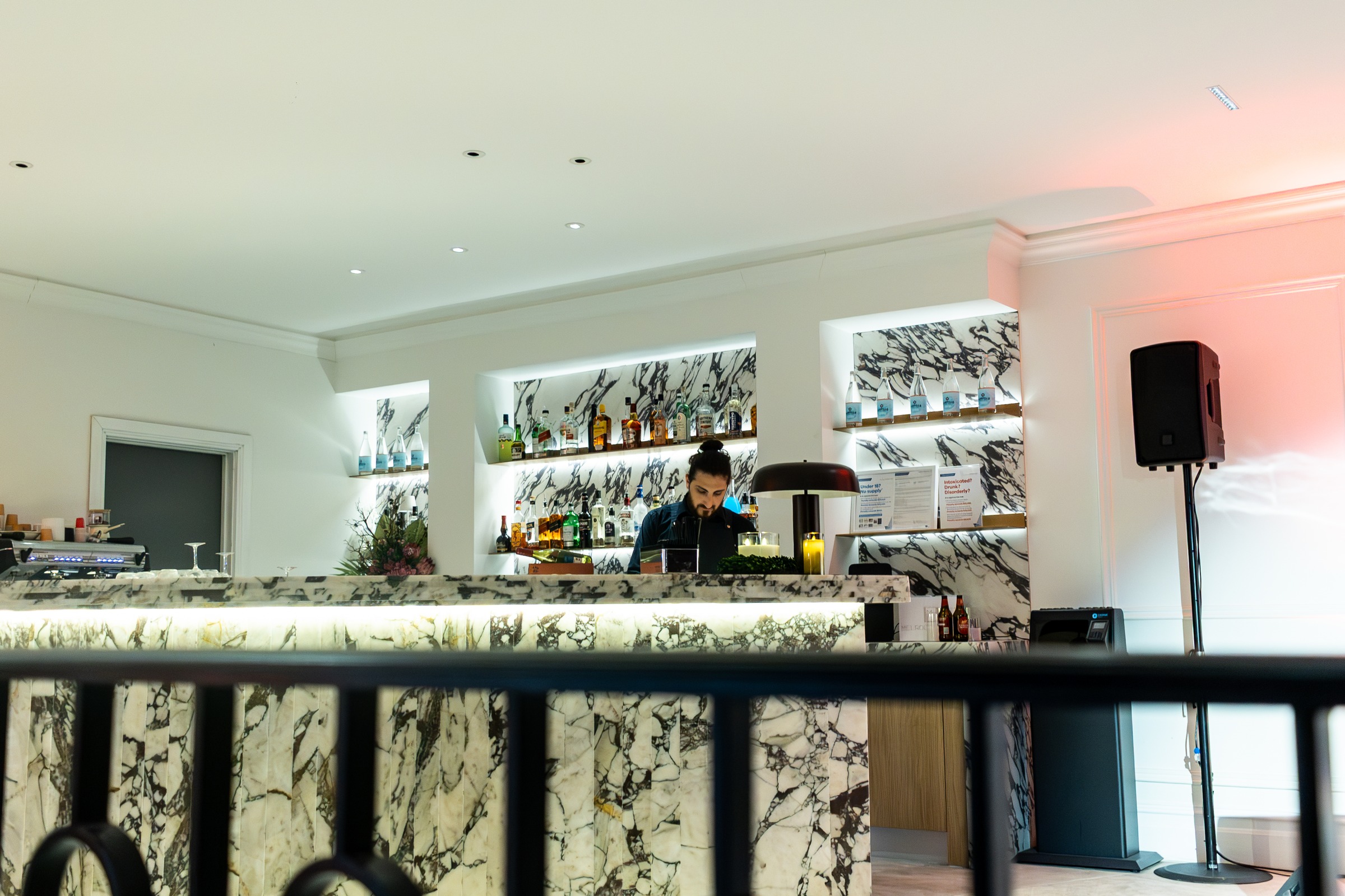 Marble bar with backlit shelving and bartender at Melrose Events