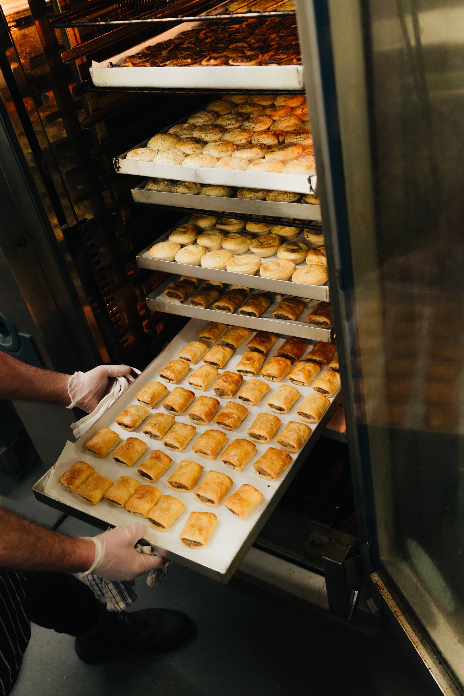Chef pulling a tray of golden pastries from the commercial oven