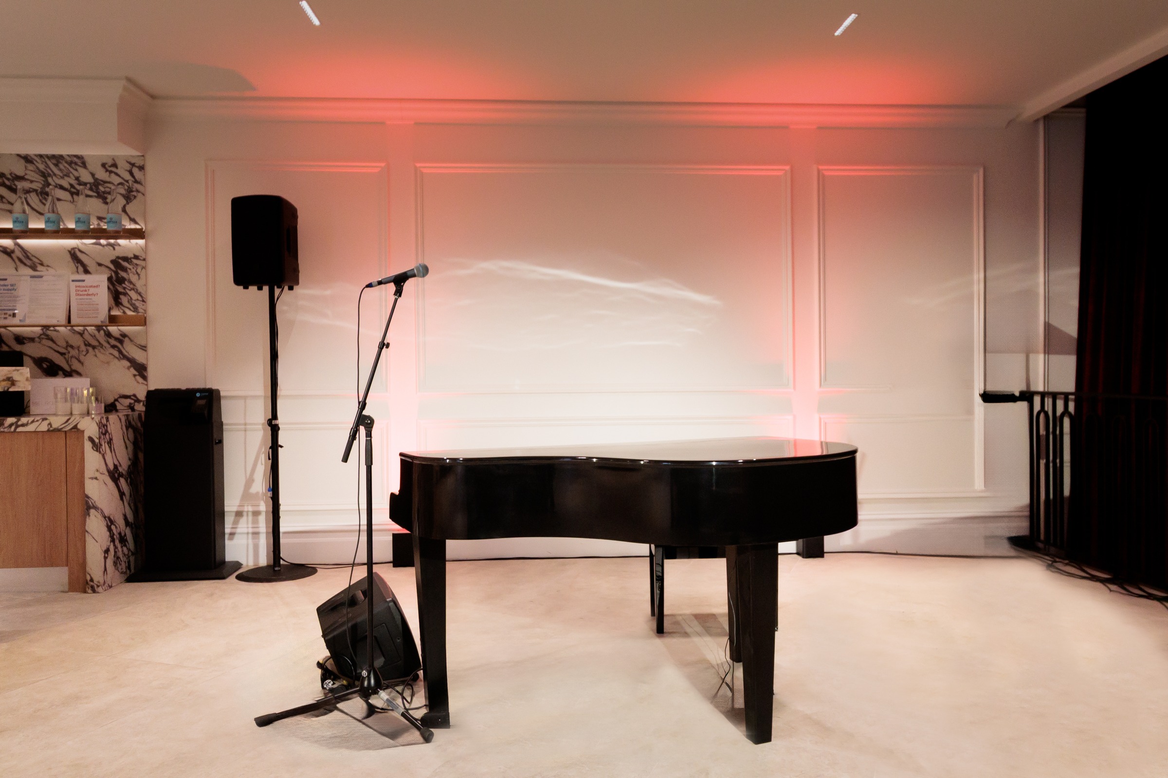 Grand piano and microphone set up under red lighting for a live performance