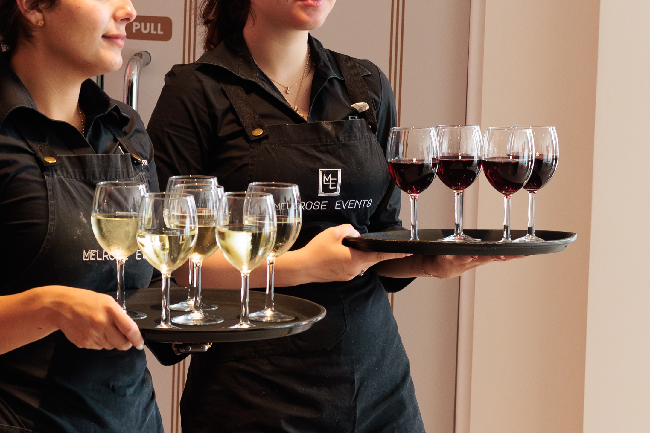 Melrose Events staff carrying trays of red and white wine for guests
