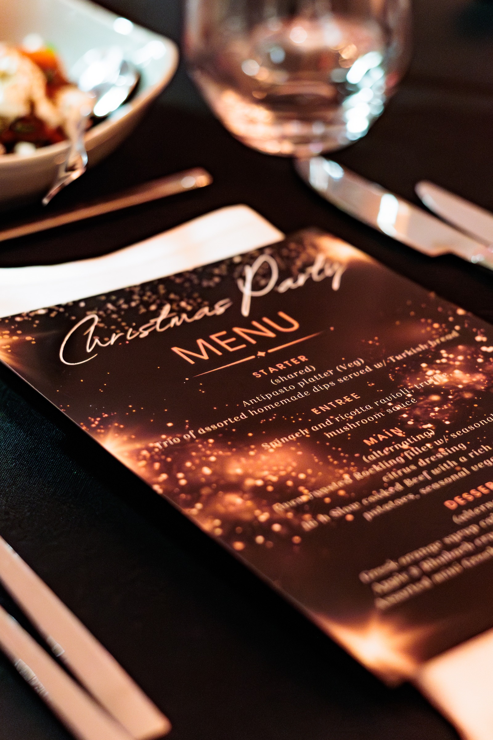 Printed Christmas party menu on a black-linen table setting